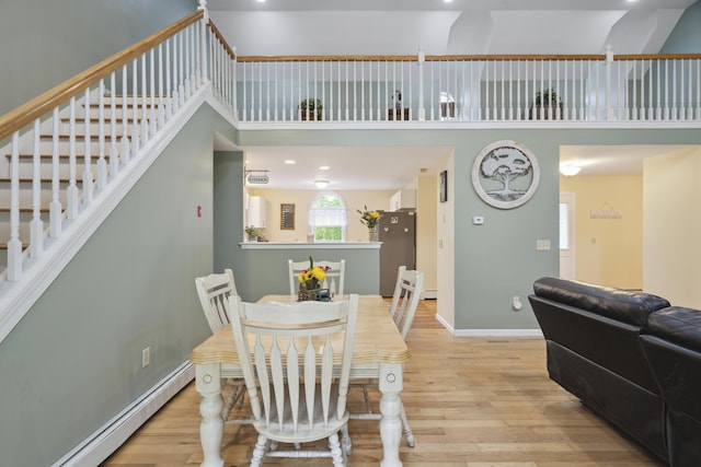 44 Emery Mills Rd, Lebanon, ME 04027 - dining room featuring a baseboard heating unit, wood finished floors, stairs, baseboards, and a towering ceiling