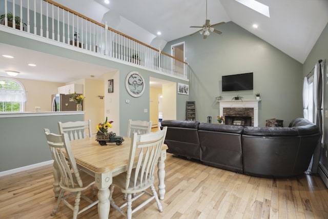 44 Emery Mills Rd, Lebanon, ME 04027 - dining space with high vaulted ceiling, light wood-style flooring, a fireplace, a ceiling fan, and a skylight