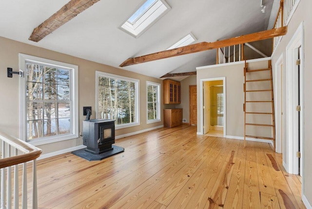 24 Cassella Dr, Jefferson, ME 04348 - unfurnished living room featuring a wood stove, a skylight, stairway, light wood finished floors, and baseboards