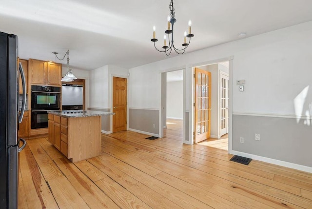 24 Cassella Dr, Jefferson, ME 04348 - kitchen featuring freestanding refrigerator, light wood finished floors, a chandelier, decorative light fixtures, and a center island