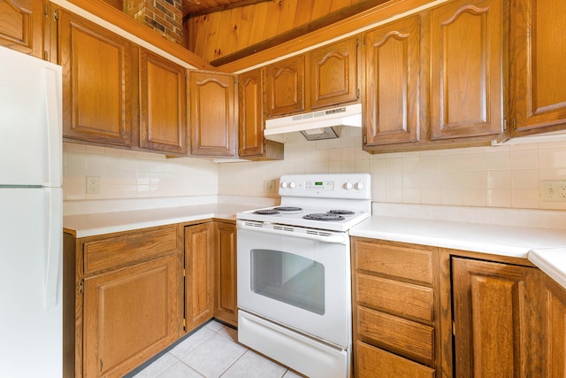 37 Boulder Dr, Auburn, ME 04210 - kitchen with white appliances, under cabinet range hood, tasteful backsplash, and brown cabinetry