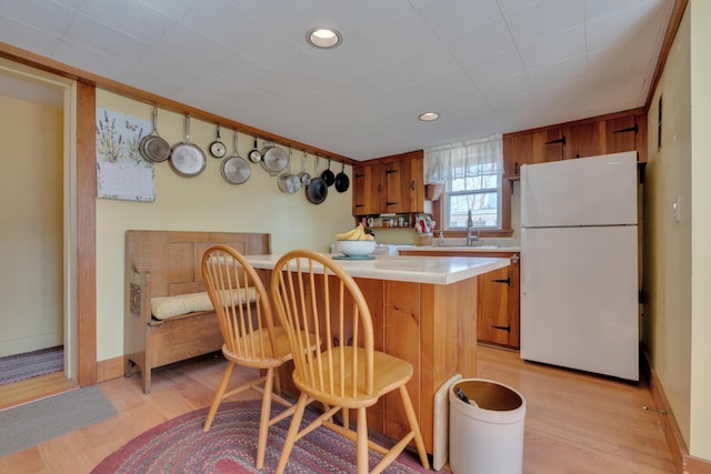 25 Church St, Gorham, ME 04038 - kitchen featuring freestanding refrigerator, brown cabinets, light countertops, light wood-type flooring, and a breakfast bar area