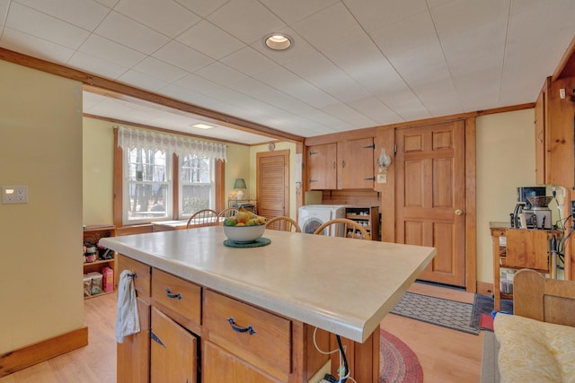 25 Church St, Gorham, ME 04038 - kitchen with washing machine and clothes dryer, light wood finished floors, light countertops, a center island, and ornamental molding