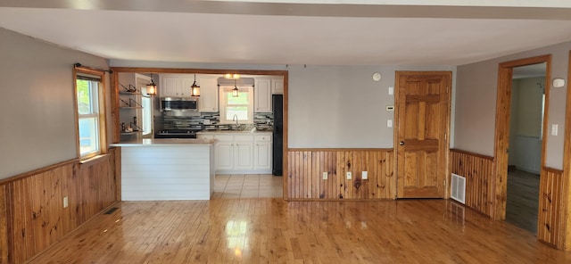 162 30th St, Shapleigh, ME 04076 - kitchen featuring a wainscoted wall, wooden walls, black refrigerator, white cabinets, and light wood finished floors