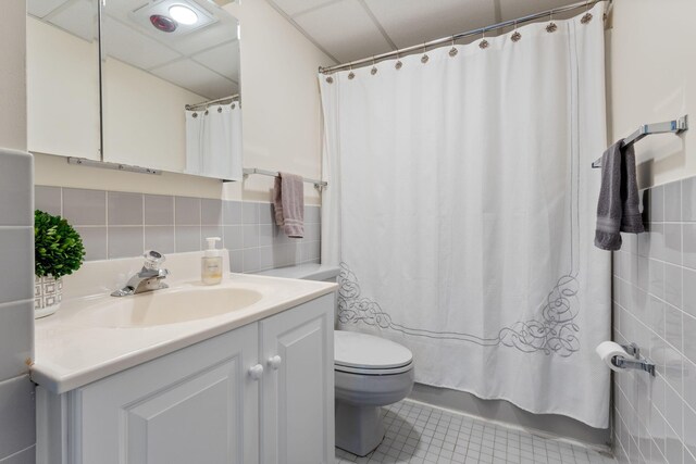 31 E Grand Ave Unit 80, Old Orchard Beach, ME 04064 - bathroom with vanity, a paneled ceiling, toilet, tile patterned floors, and tile walls
