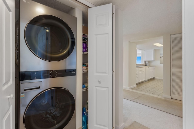 31 E Grand Ave Unit 80, Old Orchard Beach, ME 04064 - laundry area featuring stacked washer / dryer, light carpet, baseboards, and light tile patterned flooring