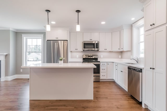 186 Falcon Crest Dr Unit 57, Gorham, ME 04038 - kitchen featuring appliances with stainless steel finishes, a sink, ornamental molding, white cabinets, and a kitchen island