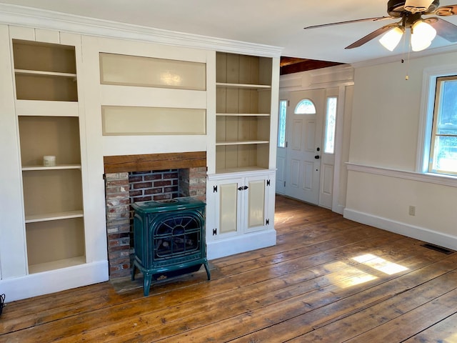 48 River Rd, Buxton, ME 04093 - unfurnished living room with a wood stove, built in shelves, hardwood / wood-style floors, ceiling fan, and crown molding