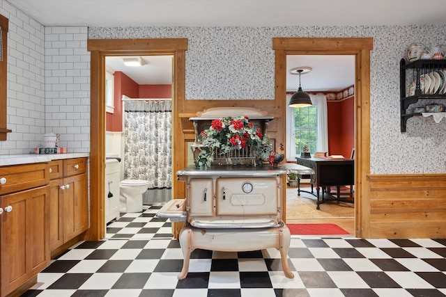 62 Blackswoods Rd, Franklin, ME 04634 - kitchen featuring tile patterned floors, brown cabinetry, a wainscoted wall, wallpapered walls, and wooden walls