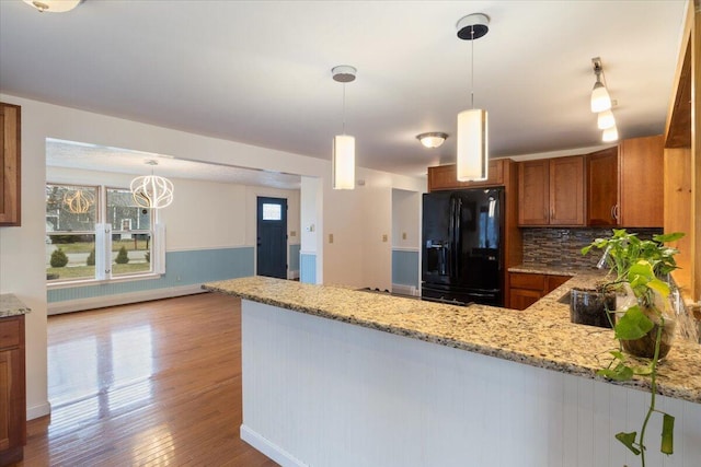 4 Buttonwood Rd, South Berwick, ME 03908 - kitchen featuring black fridge with ice dispenser, brown cabinetry, a peninsula, backsplash, and light stone counters