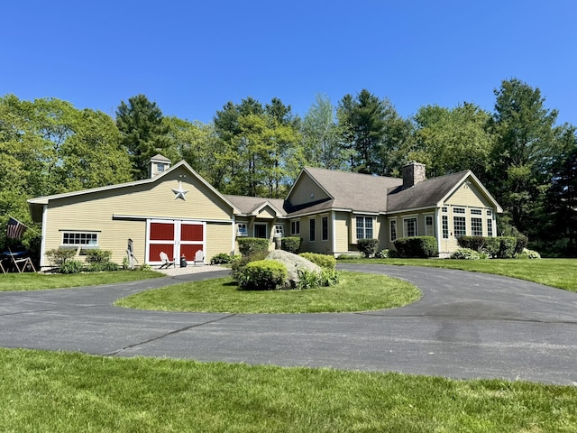 7 Ponderosa Ln, Biddeford, ME 04005 - single story home with a chimney, asphalt driveway, a front lawn, an attached garage, and view of wooded area