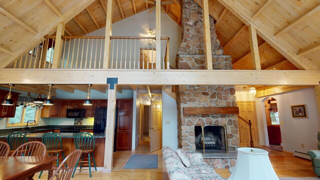 129 Maple Shore Ln, Stetson, ME 04488 - living room with light wood-style flooring, a baseboard radiator, wood ceiling with exposed beams, high vaulted ceiling, and a stone fireplace