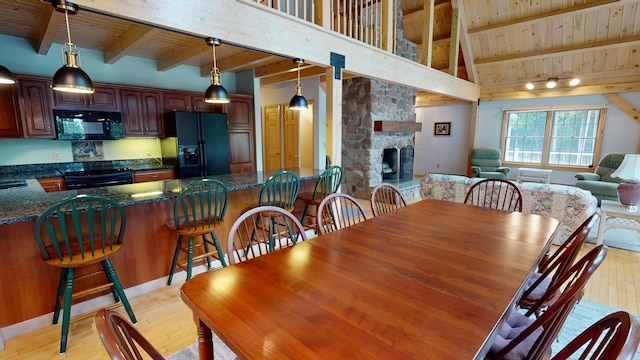 129 Maple Shore Ln, Stetson, ME 04488 - dining area featuring wood ceiling with exposed beams, light wood finished floors, and a fireplace