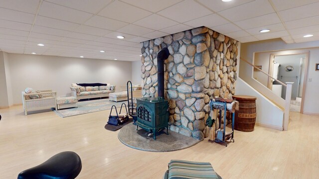 129 Maple Shore Ln, Stetson, ME 04488 - living room with a wood stove, wood finished floors, a paneled ceiling, baseboards, and stairs