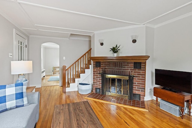 20 Donald St, Waterville, ME 04901 - living room featuring wood finished floors, arched walkways, a brick fireplace, crown molding, and baseboards