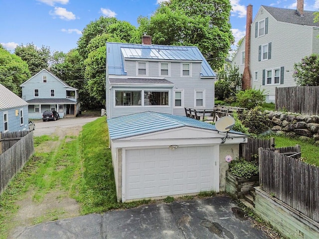 20 Donald St, Waterville, ME 04901 - view of front facade featuring a chimney, a garage, metal roof, a standing seam roof, and asphalt driveway