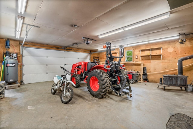 15 Convene Rd, Sebago, ME 04029 - garage with a garage door opener, a wood stove, water heater, and wood walls