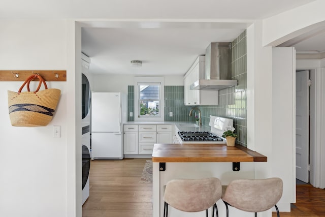 90 Wellington Rd, Portland, ME 04103 - kitchen featuring wall chimney range hood, freestanding refrigerator, wooden counters, a sink, and light wood-style floors