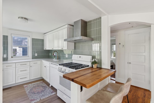 90 Wellington Rd, Portland, ME 04103 - kitchen with wall chimney range hood, white appliances, a sink, arched walkways, and dark wood-style flooring