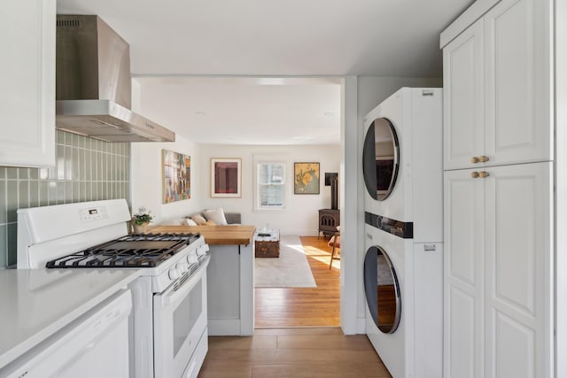 90 Wellington Rd, Portland, ME 04103 - kitchen featuring white appliances, wall chimney exhaust hood, stacked washer / dryer, open floor plan, and light wood finished floors
