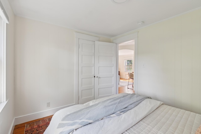 90 Wellington Rd, Portland, ME 04103 - bedroom featuring arched walkways, light wood-style flooring, baseboards, and ornamental molding