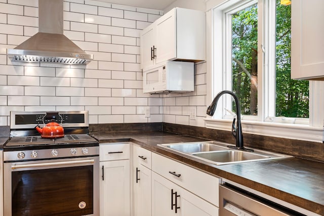 44 Yale St, Portland, ME 04103 - kitchen featuring stainless steel appliances, wall chimney exhaust hood, a sink, and dark countertops