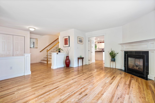 44 Yale St, Portland, ME 04103 - unfurnished living room with light wood-style flooring, stairs, a tile fireplace, and baseboards
