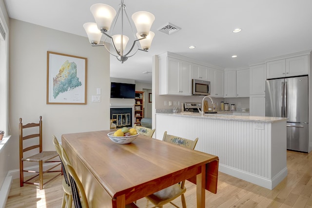 65 Pine Point Rd Unit 12, Scarborough, ME 04074 - dining area featuring light wood-style floors, a chandelier, baseboards, a glass covered fireplace, and recessed lighting