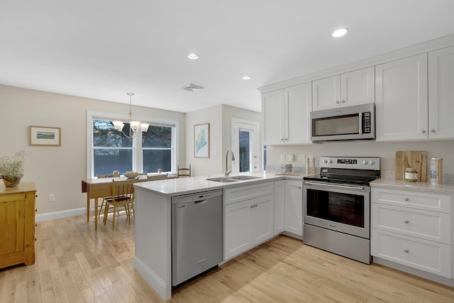 65 Pine Point Rd Unit 12, Scarborough, ME 04074 - kitchen with stainless steel appliances, a sink, white cabinetry, light wood-type flooring, and a chandelier
