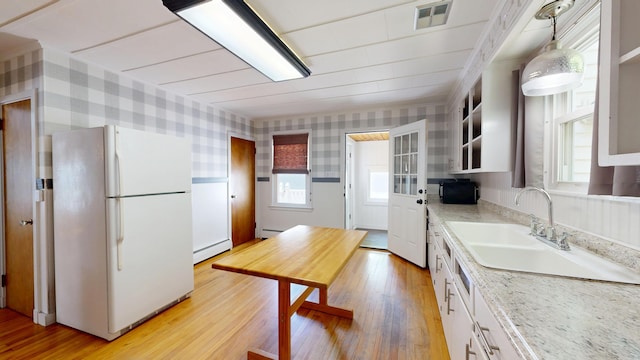 118 Riverside Dr, Auburn, ME 04210 - kitchen with freestanding refrigerator, a baseboard radiator, wallpapered walls, light wood finished floors, and black microwave