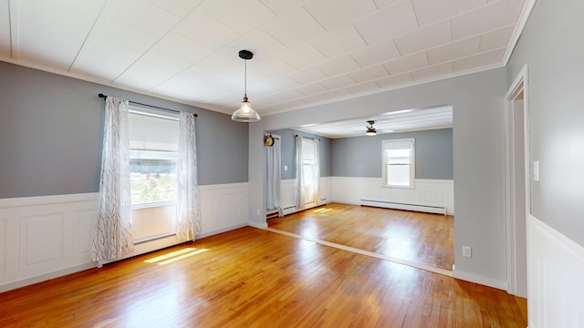 118 Riverside Dr, Auburn, ME 04210 - spare room featuring baseboard heating, light wood-style floors, wainscoting, a ceiling fan, and ornamental molding