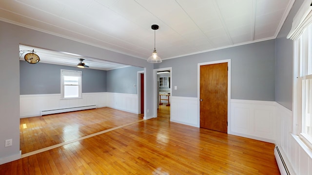 118 Riverside Dr, Auburn, ME 04210 - empty room featuring a baseboard heating unit, wainscoting, light wood finished floors, ornamental molding, and ceiling fan