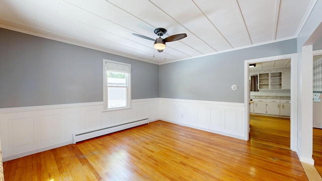 118 Riverside Dr, Auburn, ME 04210 - empty room featuring a baseboard radiator, a ceiling fan, ornamental molding, light wood-style floors, and a wainscoted wall