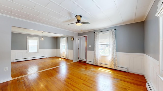 118 Riverside Dr, Auburn, ME 04210 - empty room with a baseboard heating unit, a wainscoted wall, ceiling fan, ornamental molding, and light wood finished floors