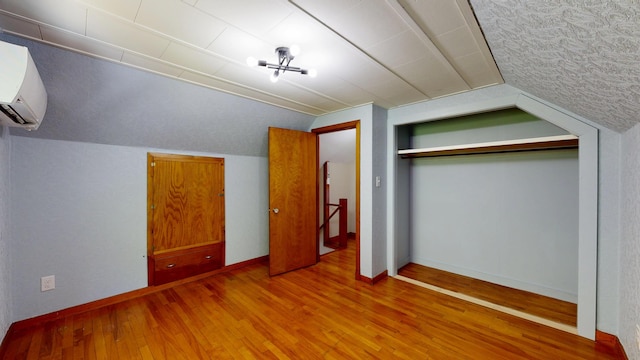 118 Riverside Dr, Auburn, ME 04210 - unfurnished bedroom featuring wood finished floors, lofted ceiling, an AC wall unit, a closet, and baseboards