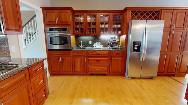 67 Joans Hill Rd, Bangor, ME 04401 - kitchen with stainless steel appliances, a sink, light wood-style flooring, tasteful backsplash, and glass insert cabinets