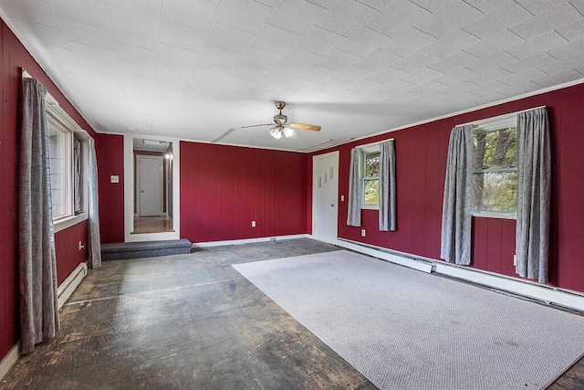 95 Riverview Dr, Gardiner, ME 04345 - unfurnished room with a baseboard heating unit, ceiling fan, concrete floors, baseboards, and wood walls