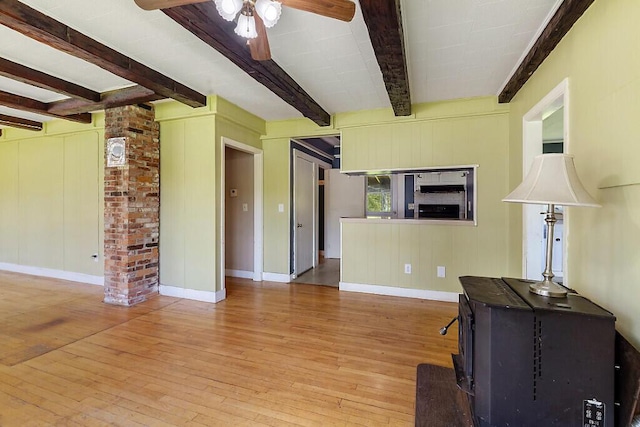 95 Riverview Dr, Gardiner, ME 04345 - living area featuring beam ceiling, wood-type flooring, ceiling fan, baseboards, and a wood stove