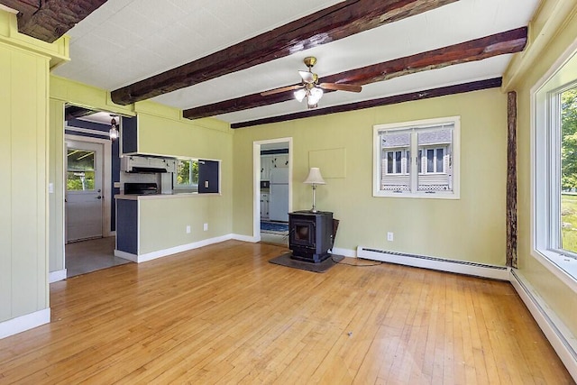 95 Riverview Dr, Gardiner, ME 04345 - unfurnished living room featuring hardwood / wood-style floors, a ceiling fan, beam ceiling, a wood stove, and baseboards