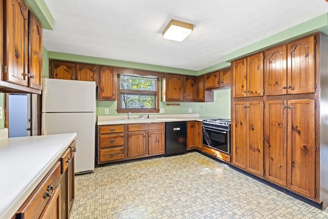 1 Fall St, Biddeford, ME 04005 - kitchen with freestanding refrigerator, black dishwasher, gas stove, brown cabinets, and a sink