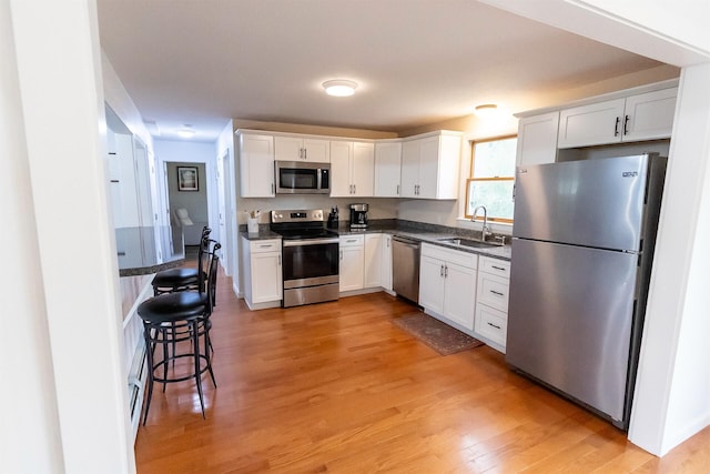 22 Penn Ave, Portland, ME 04103 - kitchen featuring stainless steel appliances, a sink, light wood-style flooring, and white cabinetry