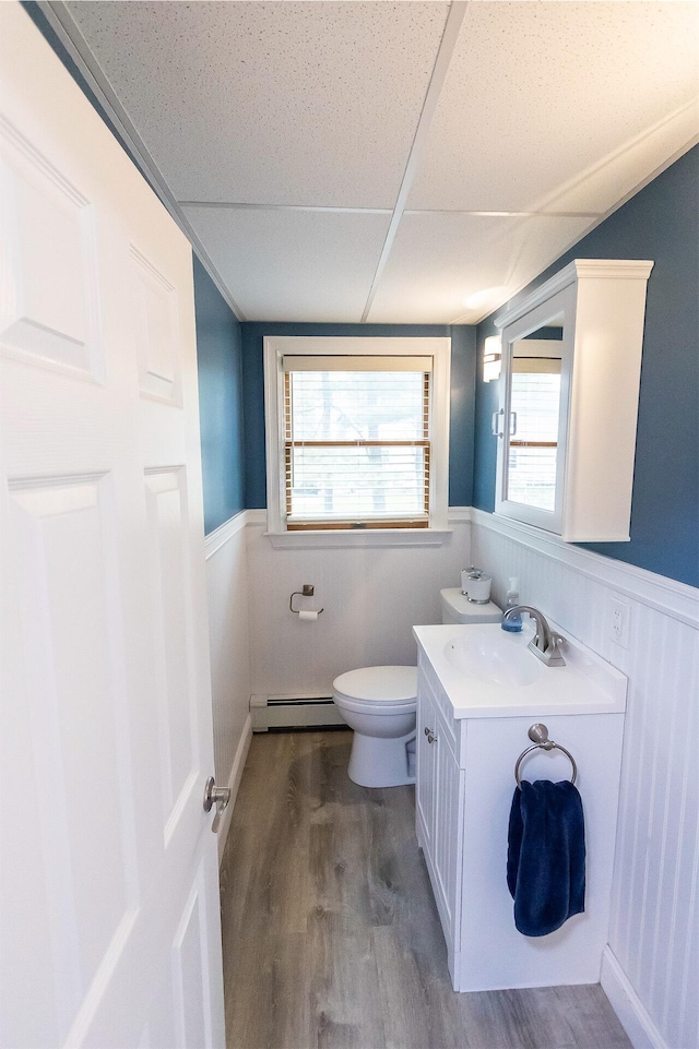 22 Penn Ave, Portland, ME 04103 - half bath with a baseboard radiator, wainscoting, toilet, wood finished floors, and vanity