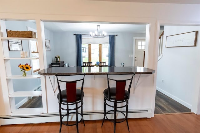 22 Penn Ave, Portland, ME 04103 - kitchen with a chandelier, dark wood-style flooring, a baseboard radiator, a kitchen bar, and dark countertops