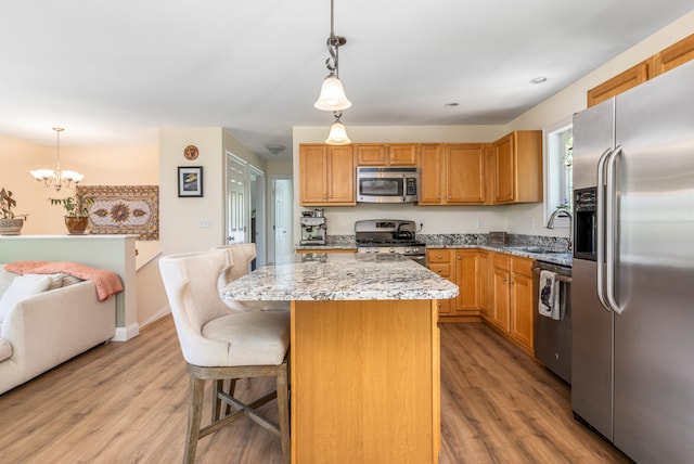 13 Daggett St, Portland, ME 04103 - kitchen with appliances with stainless steel finishes, a sink, light wood-style flooring, light stone countertops, and a chandelier