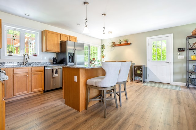 13 Daggett St, Portland, ME 04103 - kitchen featuring stainless steel appliances, a sink, light stone counters, light wood-style floors, and a center island