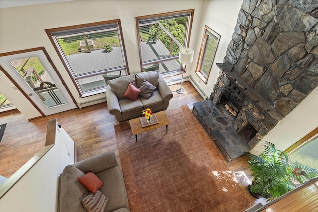 23 Stovers Point Rd, Harpswell, ME 04079 - living area with wood finished floors, a baseboard heating unit, and a stone fireplace