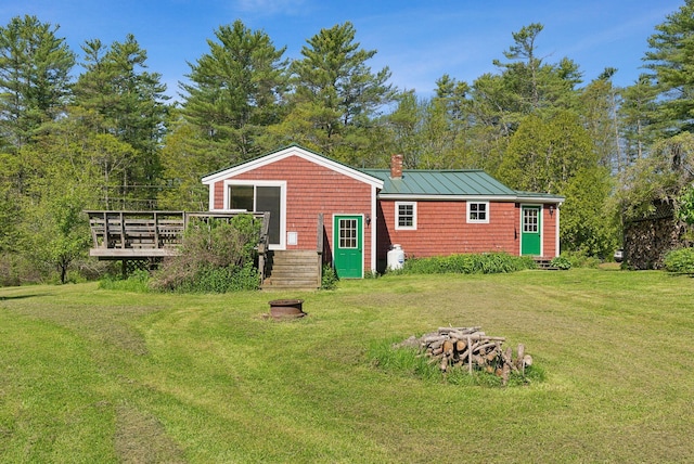 592 Old Stage Rd, Arrowsic, ME 04530 - rear view of house with a chimney, a deck, a standing seam roof, a lawn, and metal roof