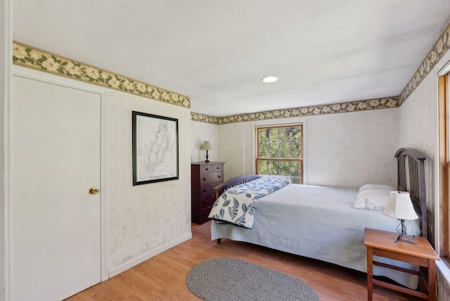 592 Old Stage Rd, Arrowsic, ME 04530 - bedroom with wallpapered walls, wood finished floors, a textured ceiling, and baseboards