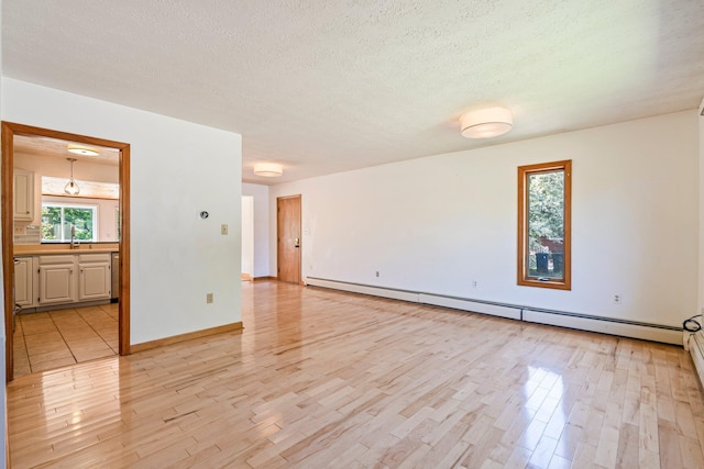 94 Thompson St, South Portland, ME 04106 - spare room featuring a baseboard heating unit, light wood-style floors, a textured ceiling, baseboards, and a sink