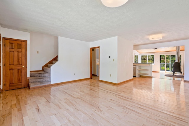 94 Thompson St, South Portland, ME 04106 - unfurnished living room featuring wood finished floors, baseboards, stairway, and a textured ceiling
